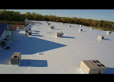 Overview of a light-colored commercial roof with rooftop equipment.